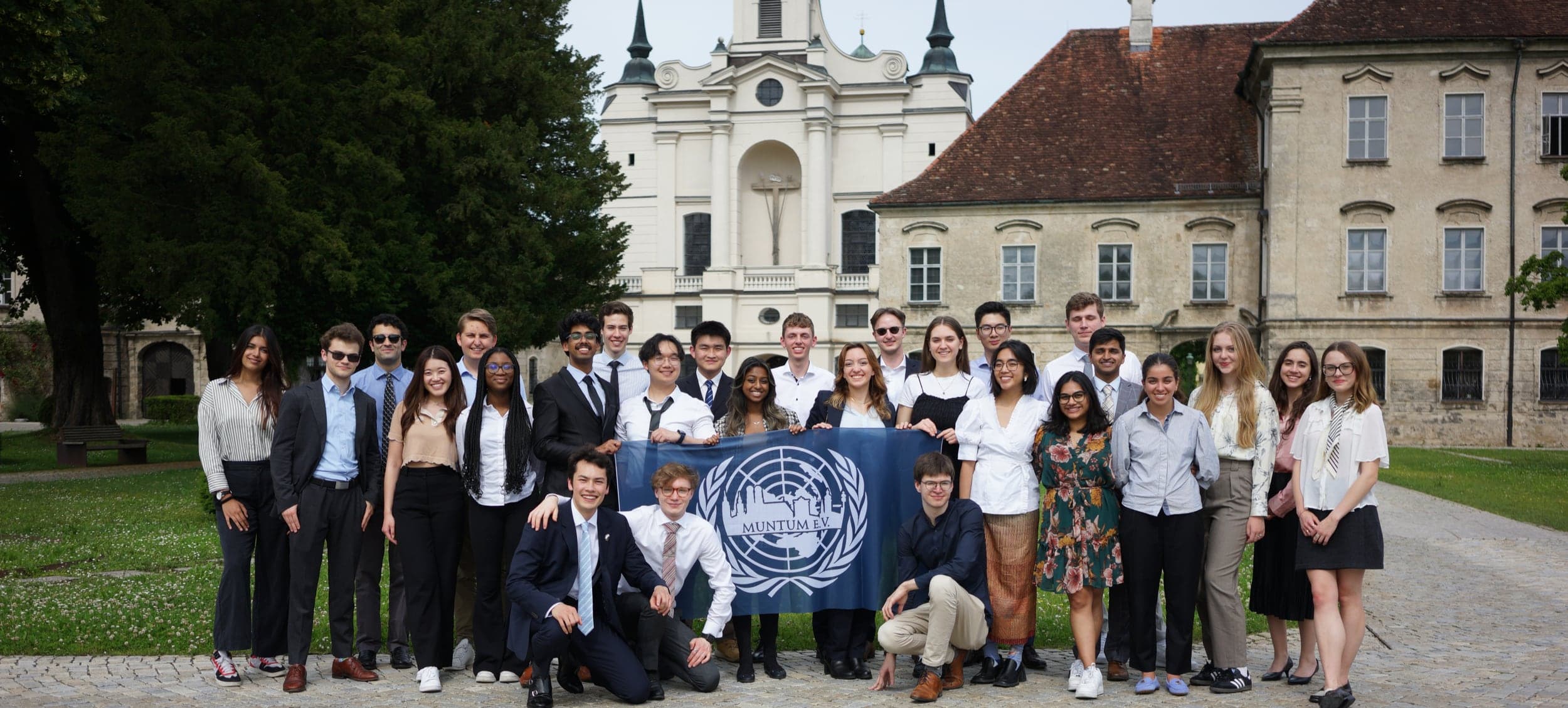 MUNTUM members with the MUNTUM flag in front of a baroque church