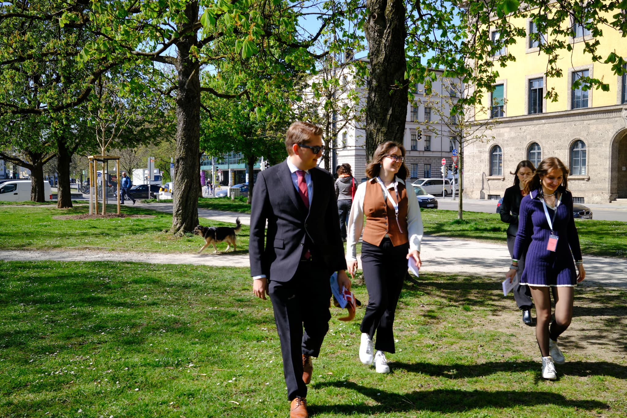 Delegates in business attire walking through a park (Munich Diplomacy Summit 2025)